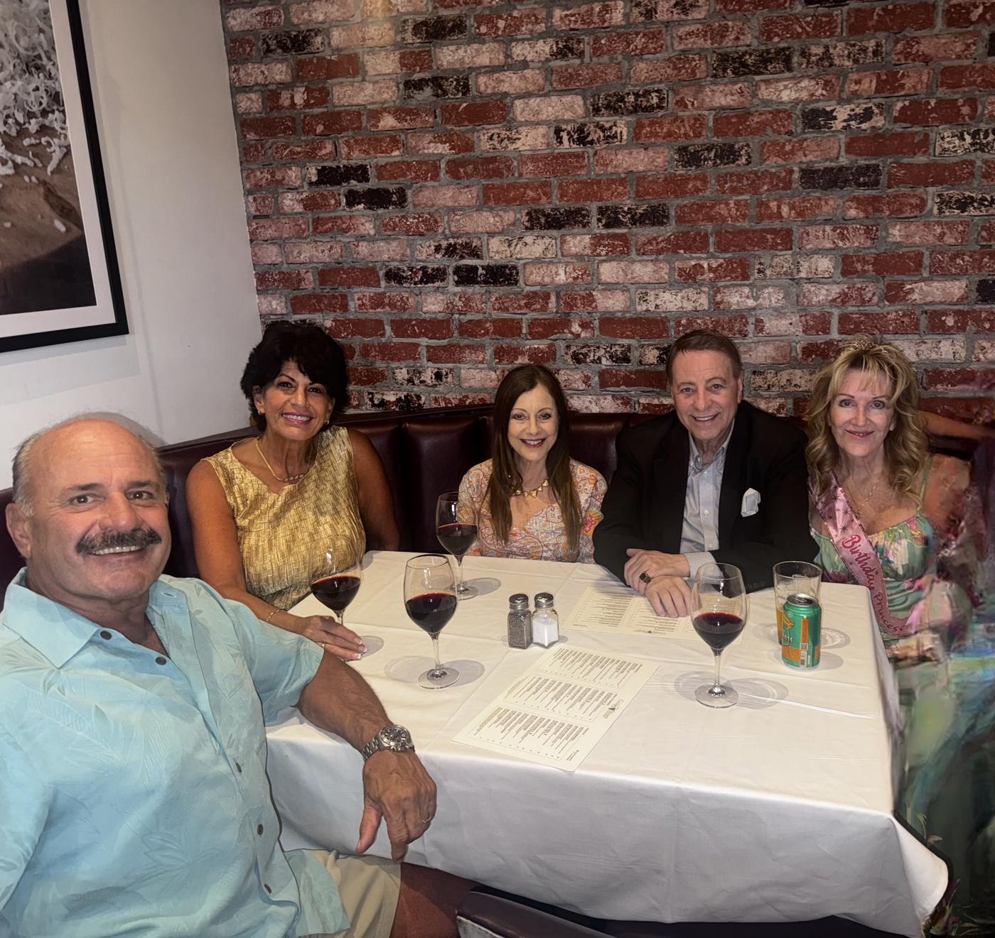 A table of smiling friends gathered for dinner and live entertainment