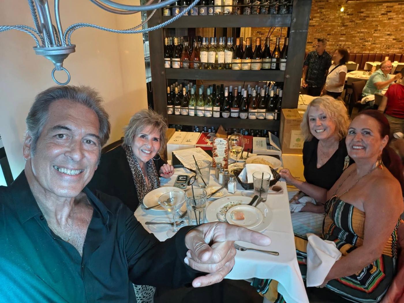 Craig with a table of friends enjoying dinner and live music