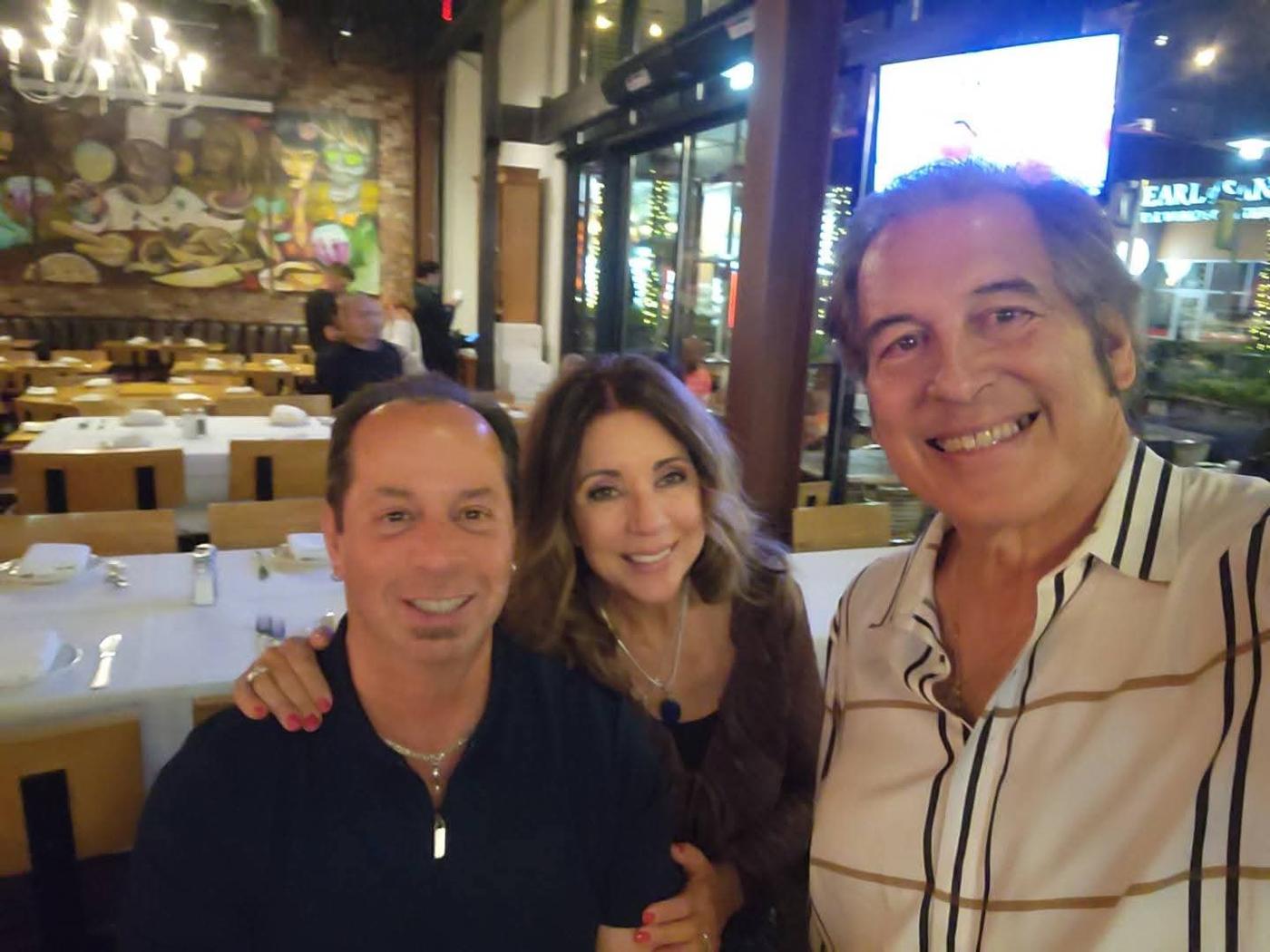 Craig smiling with two friends over dinner