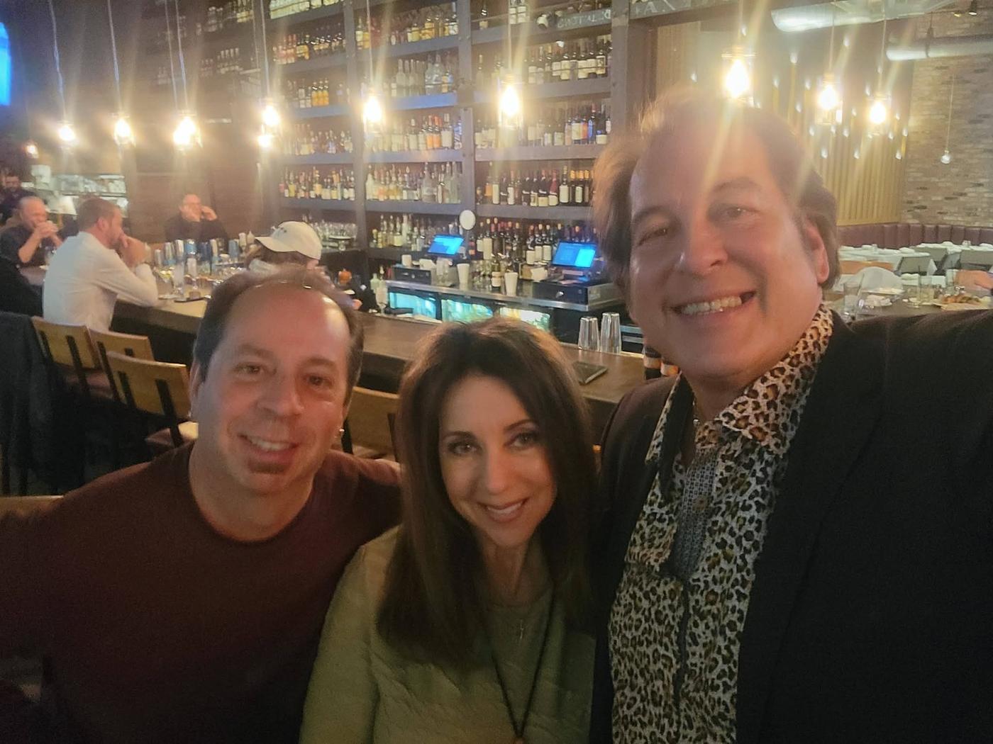 Craig smiling with two friends during an evening out